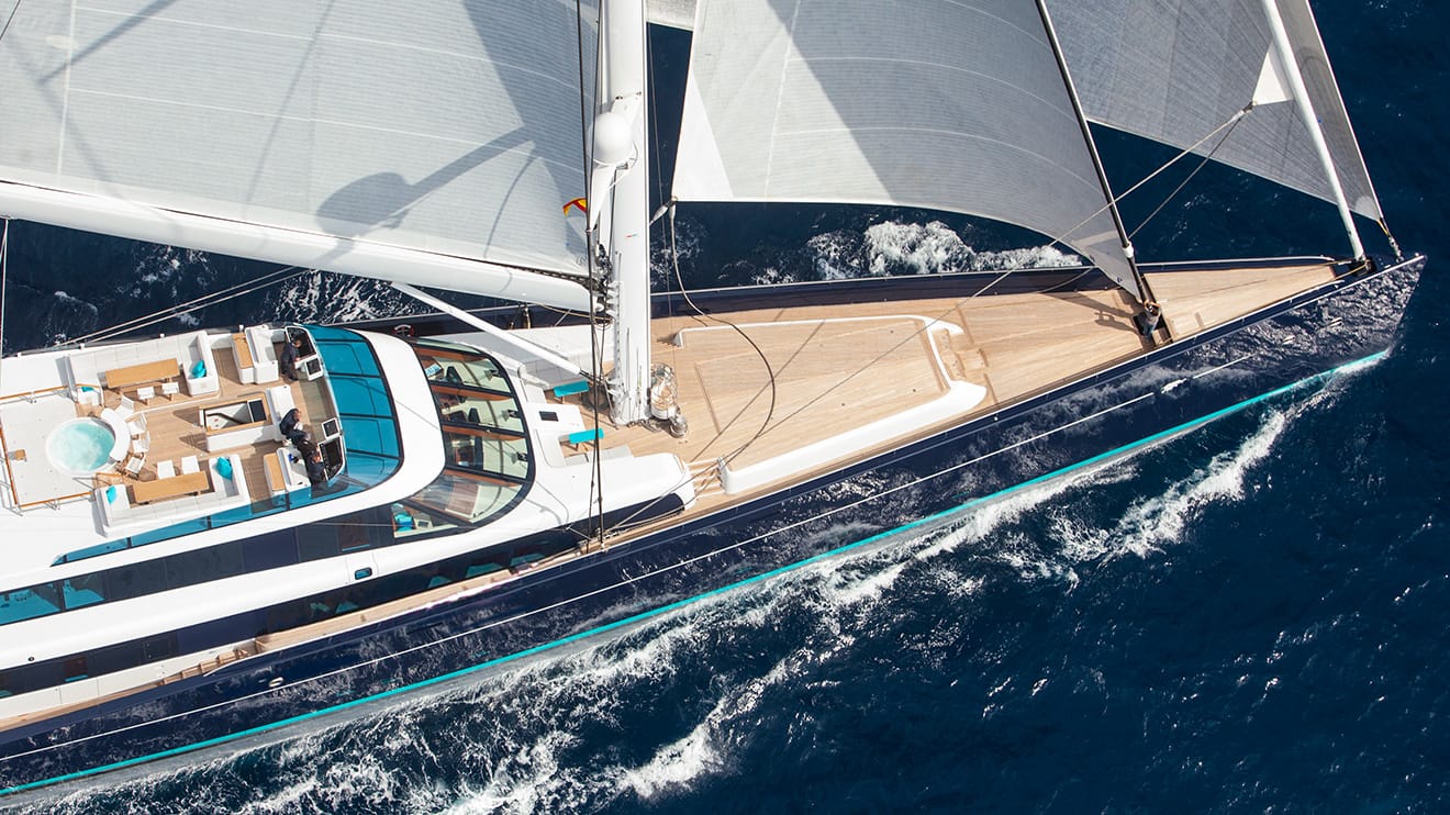 Aerial view of a sailing mega yacht for sale, highlighting its expansive deck and sleek modern design.