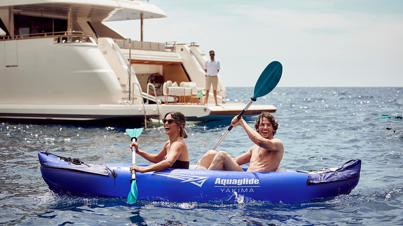 Couple kayaking near their superyacht charter, enjoying the sea on a sunny day.