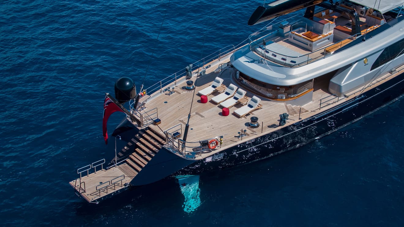 Aerial view of a superyacht charter with a spacious deck and sun loungers at sea.