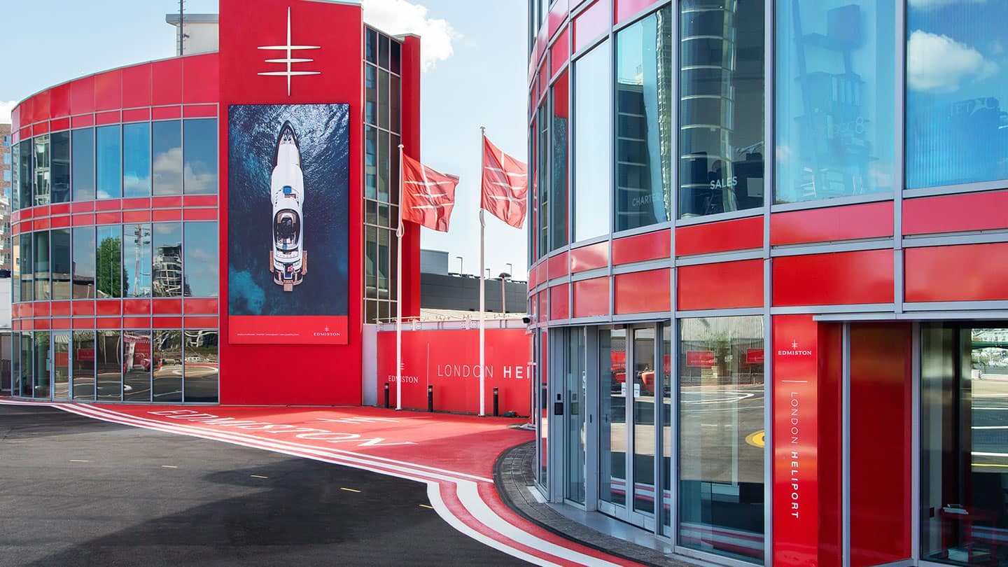Red modern office building with Edmiston branding, promoting luxury superyacht brokers.