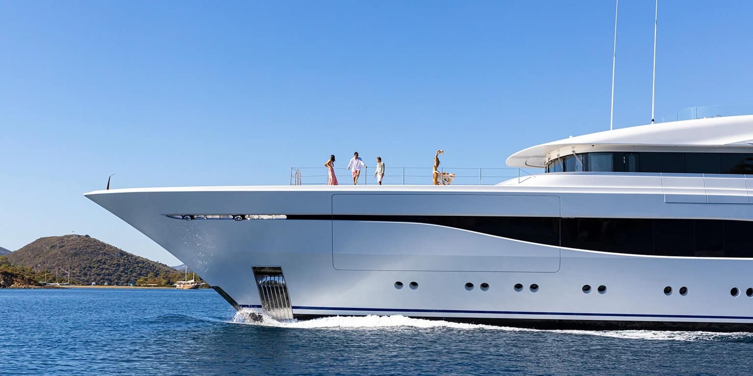 Mega yacht brokers assist friends relaxing on their new yacht, with a majestic ocean view in the background.