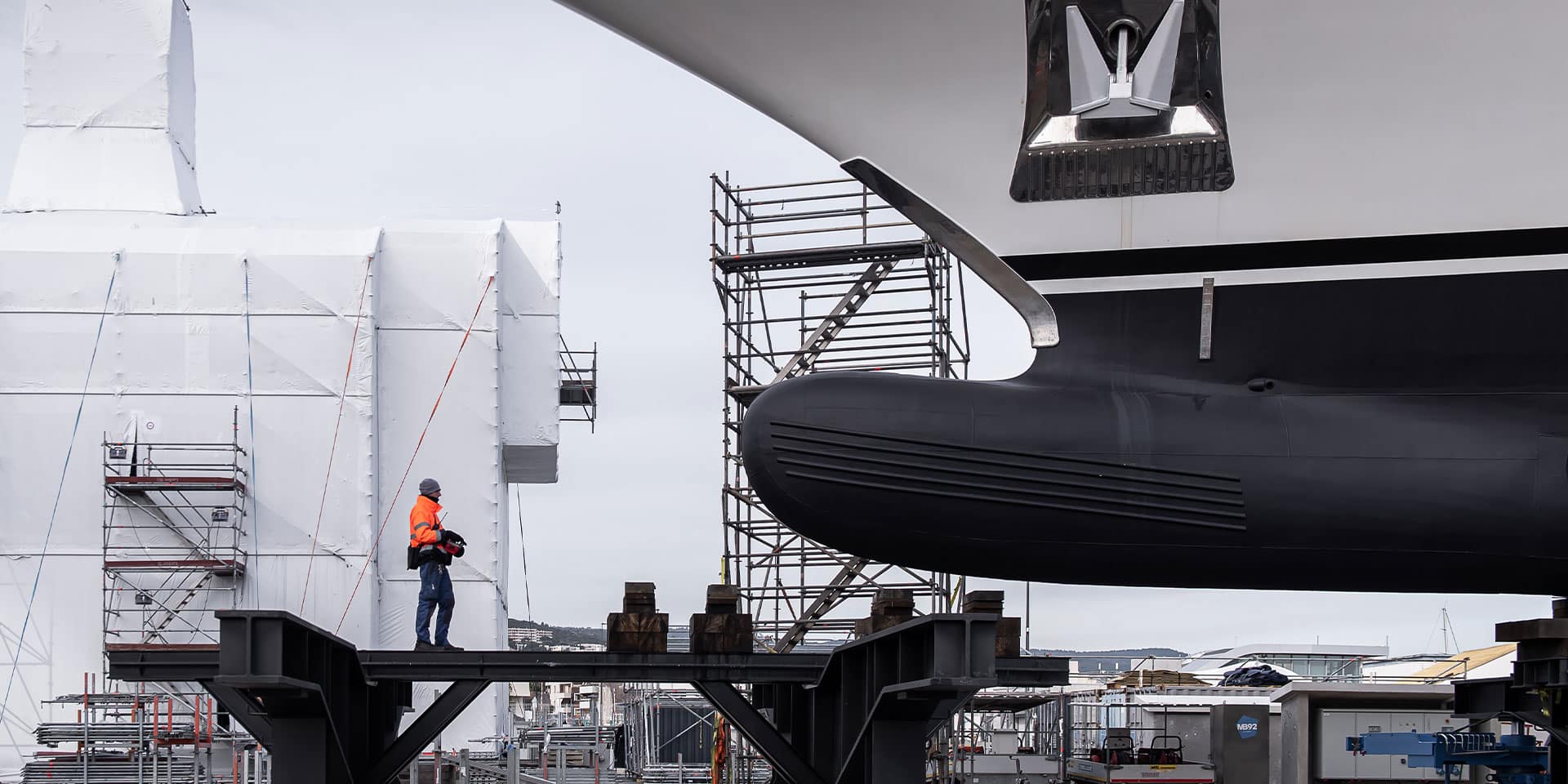 Worker inspects a vessel in construction, highlighting expert servicing of luxury yachts for sale.