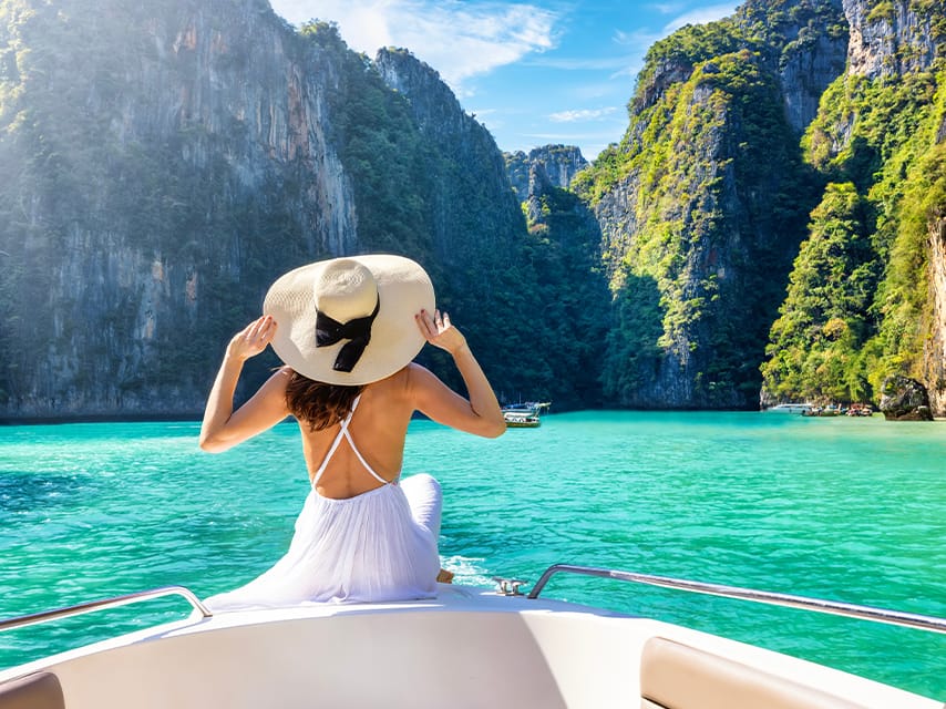 A woman in her tender approaches towering limestone cliffs in Thailand during one of her favourite private yacht vacations.