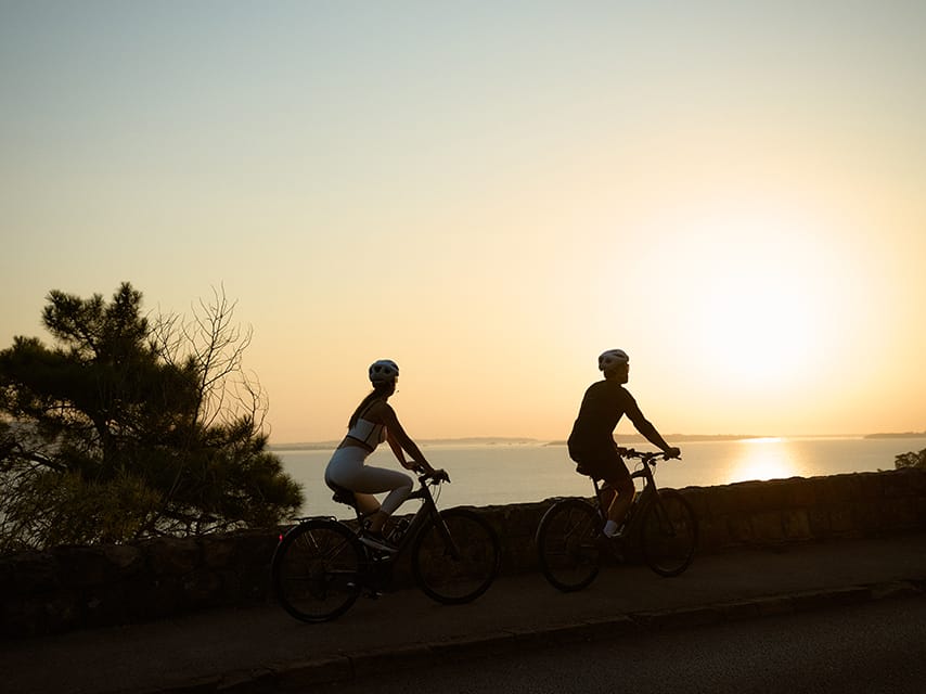 A couple ride bikes, relishing in the yacht activities and bucket list experiences they enjoy from their private yacht, Bali.