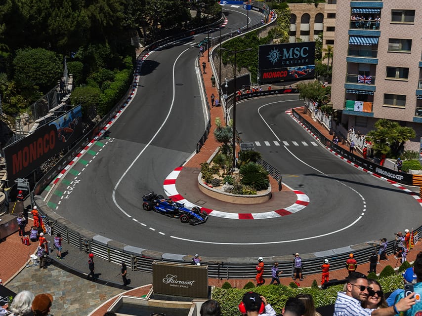 A blue race car drives the Monaco Grand Prix track. Enjoy this luxury event in 2025 from a superyacht charter with Edmiston.