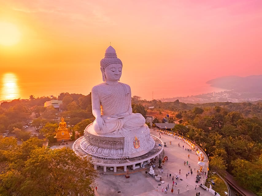 The sun sets over a Big Buddha statue in Phuket, a must-see cultural gem during your private yacht Phuket experience.