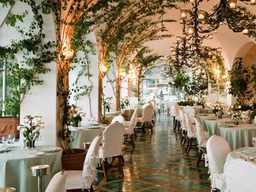 Experience La Sponda’s magical ambiance with draping bougainvillea and hundreds of suspended candles at a famous restaurant in Europe.