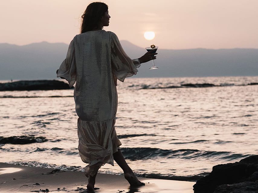 Relaxing with a drink, a woman soaks in the serene vibes of Cabana Mare Crete during her mega yacht charter in Greece.