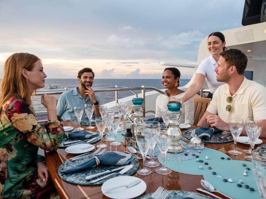 Guests enjoy sunset dinner on deck, highlighting a stylish Greek island hopping yacht experience.