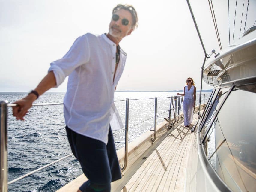A couple gazes at the horizon, soaking in the beauty of a Greek island trip by yacht.