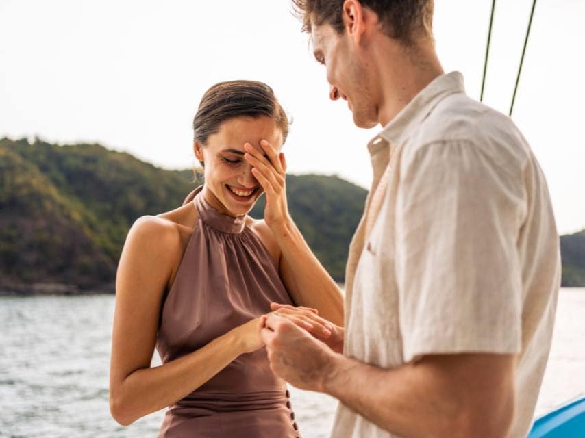 A man proposes to his love on the yacht balcony, a romantic moment surrounded by ocean views and yacht romance.