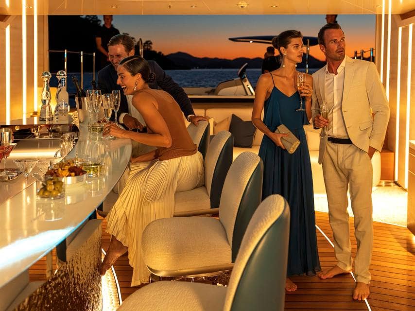 Friends gather around Arrow's bar at golden hour during a luxury wedding venue at sea.