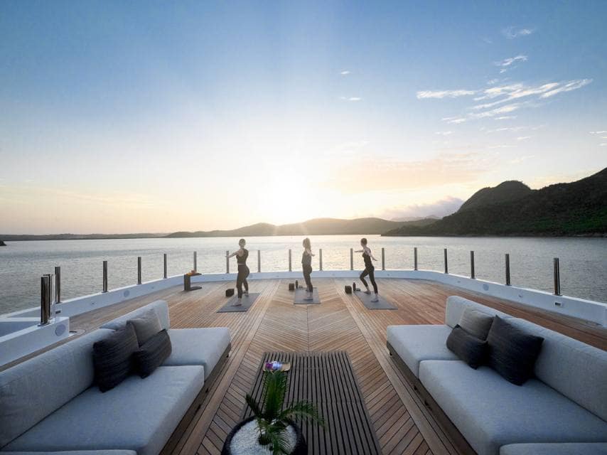 Women meditate and stretch on the ARBEMA sundeck, preparing for a day filled with luxury and romance at their private yacht wedding.