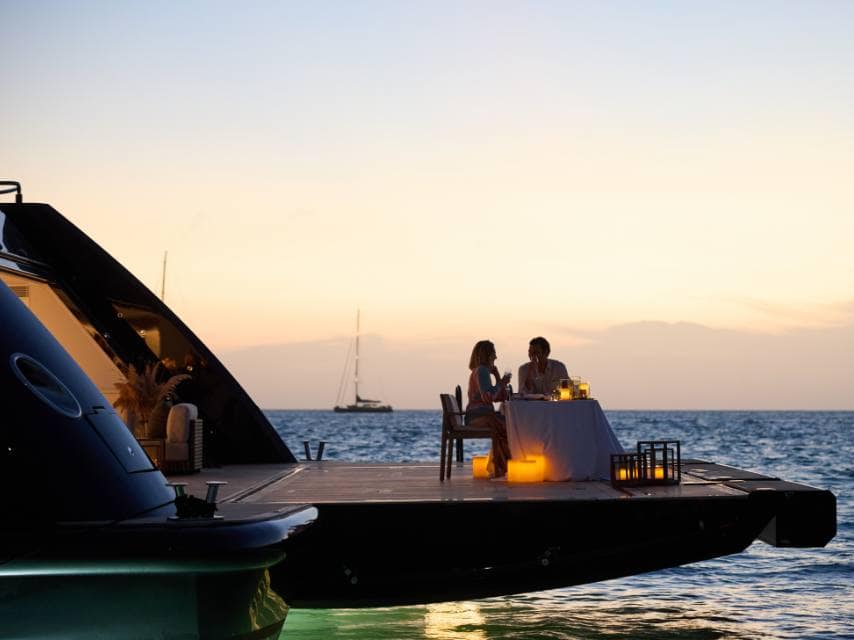 Bride and groom enjoy a romantic candlelit dinner on one of the most romantic getaways aboard a luxury yacht.