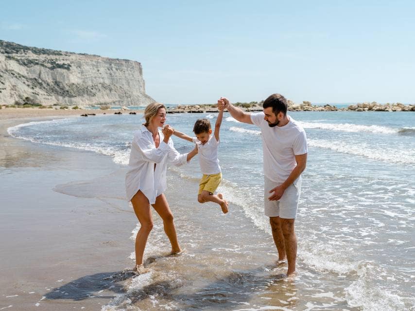 A happy family walks along the beach on a secret cave exploration during a superyacht charter, Mediterranean.