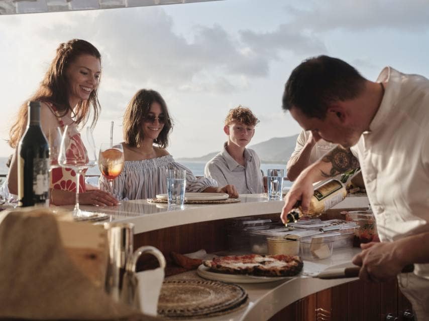 Charter guests enjoying wood-fired Neapolitan pizza on SOPHIA yacht during a Med yacht charter.