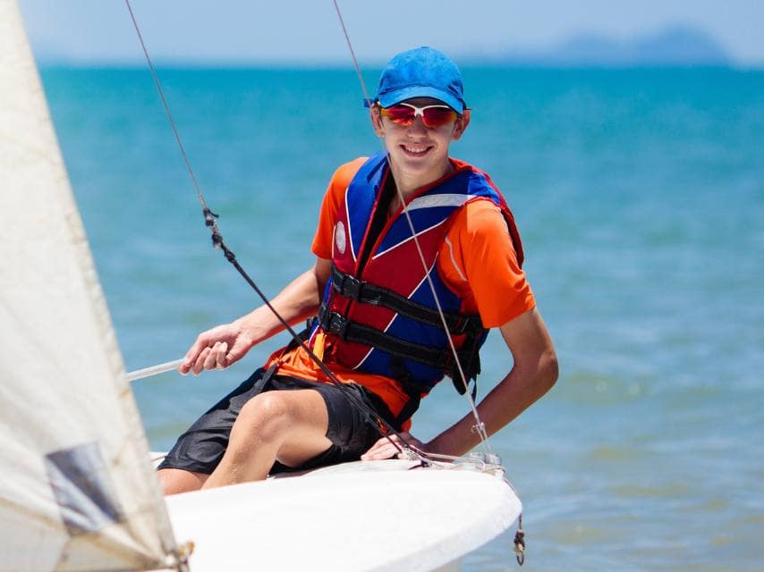 A child learns to sail a small sailing dinghy in a family sailing school during a mega yacht charter, Mediterranean