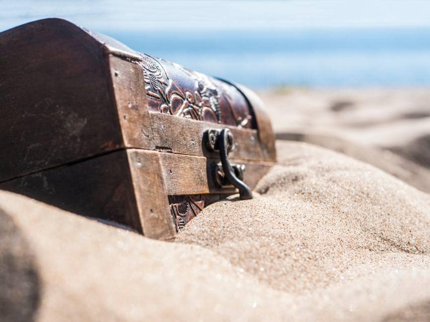 A rustic treasure chest washed up on the beach — a clue in a thrilling treasure hunt on a super yacht holiday.