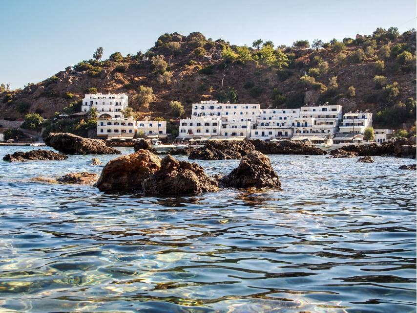 Whitewashed cliffside homes in Loutro shine under the sun — a serene stop on your Mediterranean superyacht charter.
