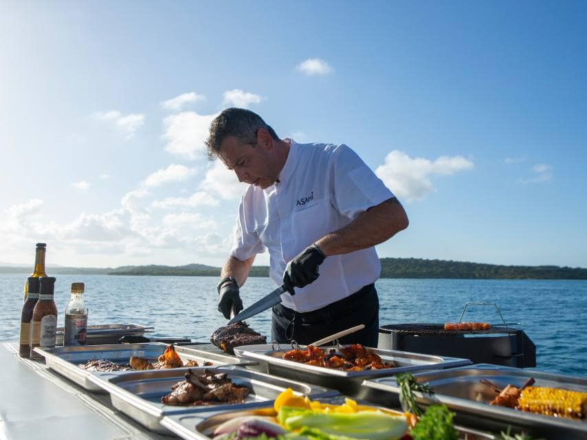 A private chef crafts gourmet dishes while guests explore mythological sites on their Greek island luxury yacht charter.