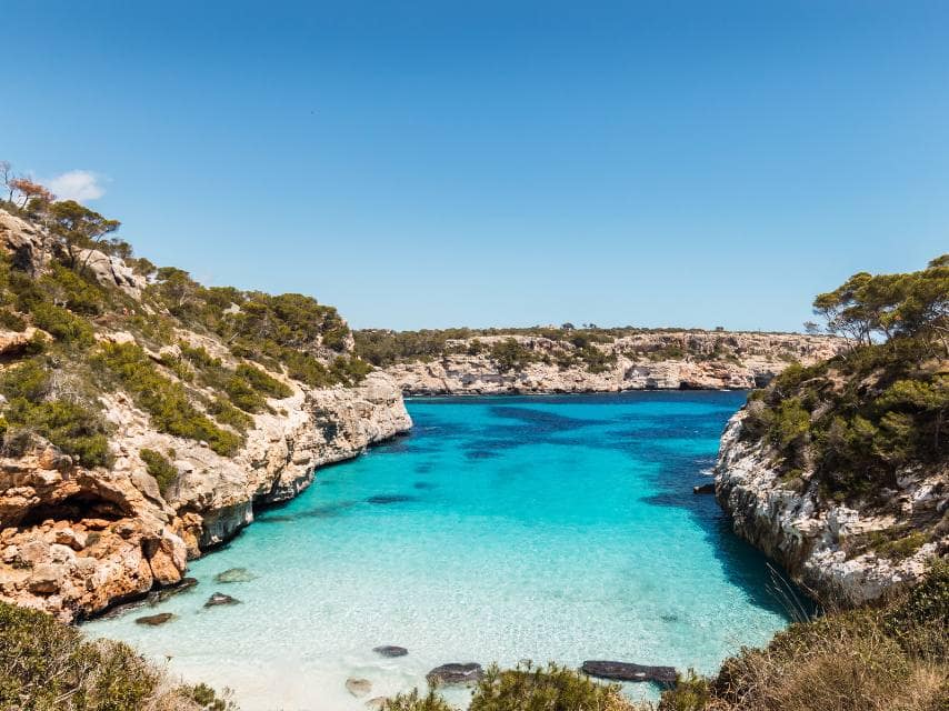 Bright blue waters and cliffs frame Calo des Moro, a hidden gem for Mediterranean sea yacht charter travelers.