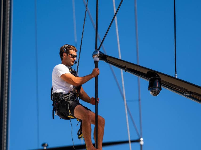 Yacht crew climbing a sail mast