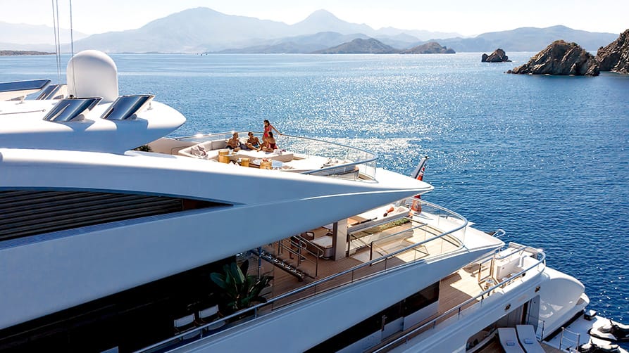 Four friends learn how to buy mega yacht, while relaxing and chatting on the deck of superyacht.