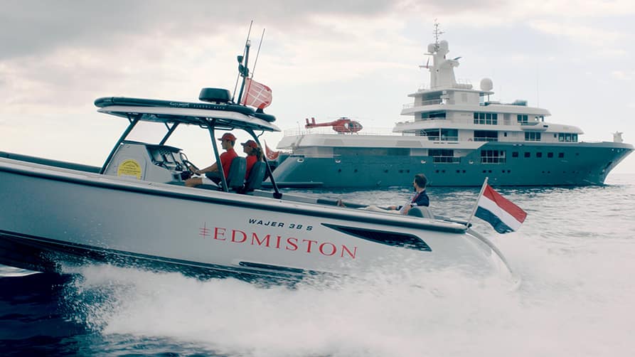 A client arrives at a yacht showcase, accompanied by an Edmiston yacht brokerage expert, highlighting the luxury experience.
