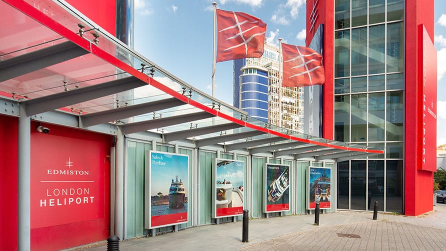 London Heliport entryway displaying Edmiston luxury yachts and flags, highlighting an exlusive experience.