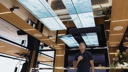 A man enjoys the view of his superyacht refit while sipping a drink, relishing the moment.