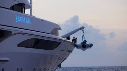 A superyacht's tender is lifted, illustrating luxury and the sleek design possible when you build your own yacht.
