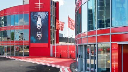 Battersea heliport red glass exterior displays an Edmiston yacht image, highlighting a luxury experience.