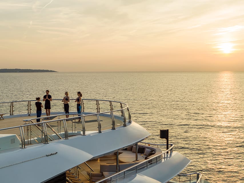 Aboard a luxury yacht, a group enjoys a wellness practice arranged by their trusted Edmiston yacht broker, Palma de Mallorca.