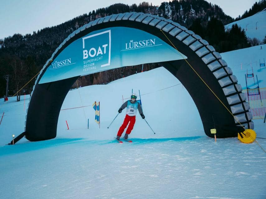 A skier crosses the finish line at a slalom event during the Superyacht Design Festival 2026 in the alpine slopes.