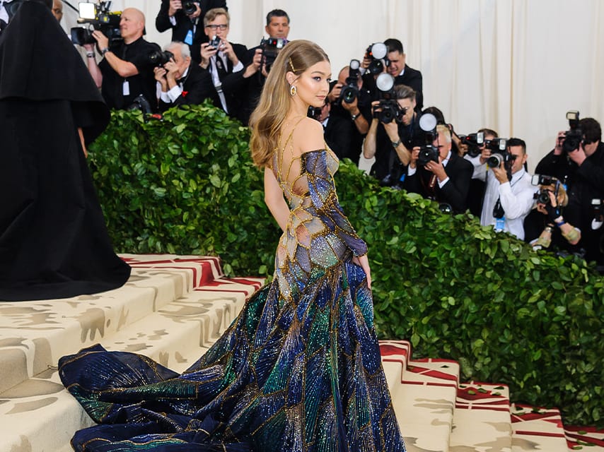 Gigi Hadid poses in a Versace Butterfly Stained Glass dress on the steps of the Met Gala, one of the top luxury events, 2025.