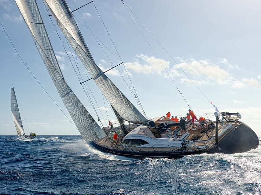 A superyacht races in the St. Barths Regatta, one of the top luxury events, 2025. View the race from a luxury yacht charter.