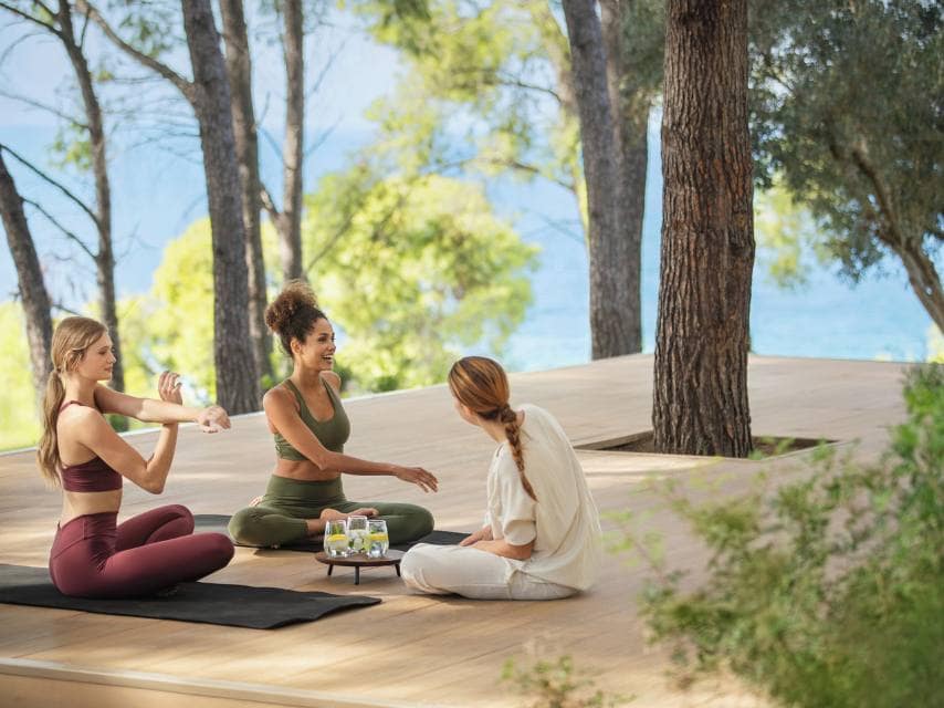 A group of women practice yoga at Sani Club Halkidiki, an elegant destination for relaxation during your mega yacht charter in Greece.