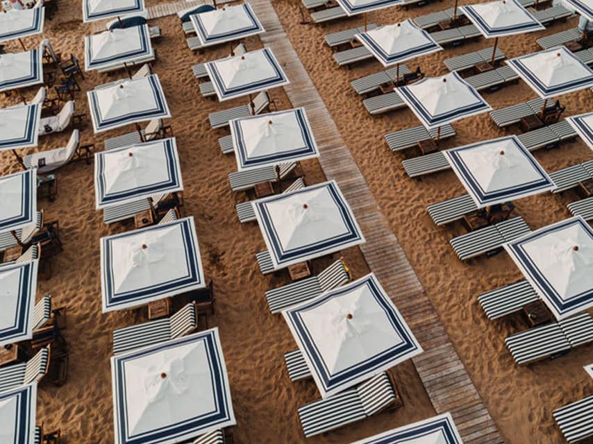 On your mega yacht charter in Greece, relax in style at Astir Beach Athens, where luxury vintage loungers and umbrellas line the beach