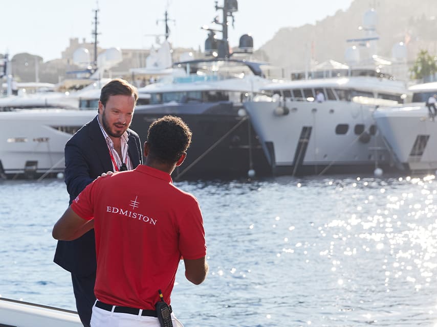 An Edmiston broker instructs crew as guests arrive to buy a yacht, Cannes setting the stage for a luxury sales experience.