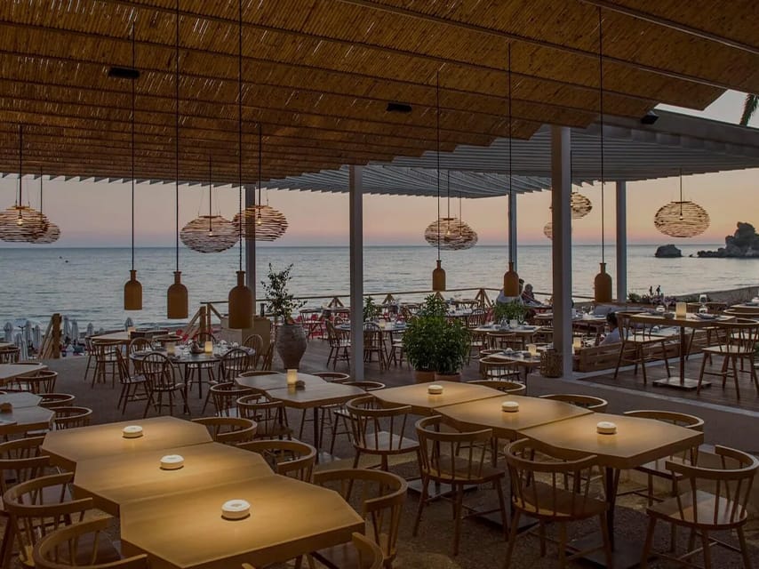 The stylish seaside dining room at Pazuzu Beach Club Corfu offers a sunset view, an unforgettable destination on your yacht charter in Greece.