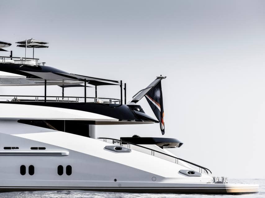 Super yacht flag waving on AHPO as it sails through calm open waters under clear skies.