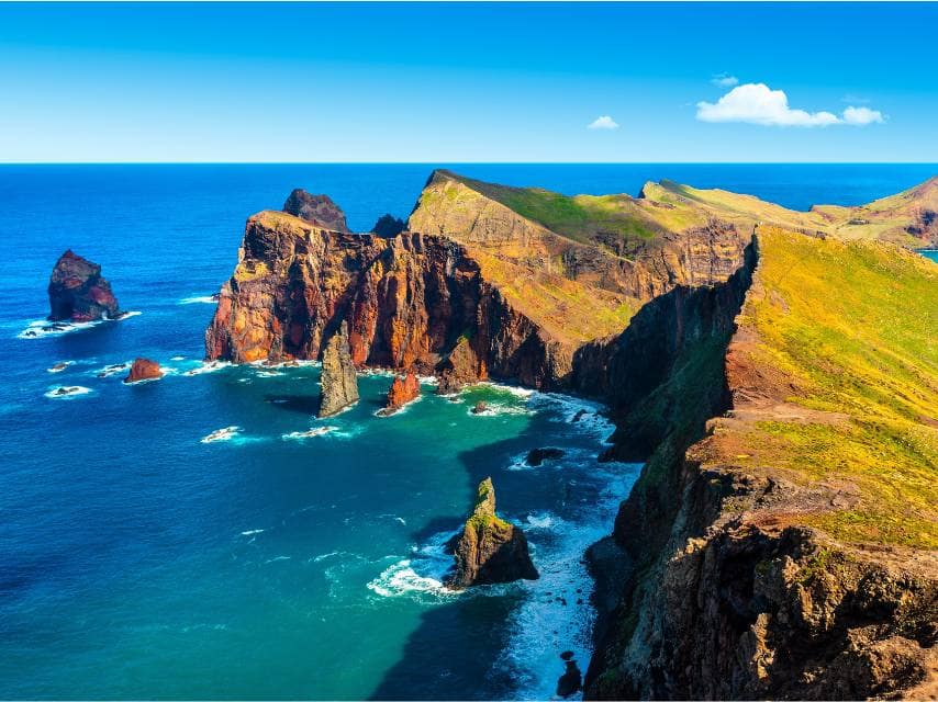 Madeira yacht charter guests explore vibrant marine life near towering rock cliffs on a guided snorkel and dive excursion.