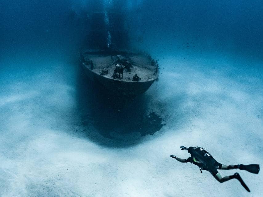 Scuba diver exploring a shipwreck near Gozo during a Cathedral Cave Gozo luxury scuba yacht charter itinerary.