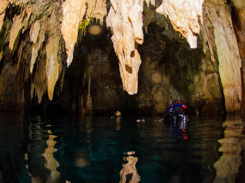 Divers explore fossilised rock formations inside Elephant Cave Crete during a private yacht charter.
