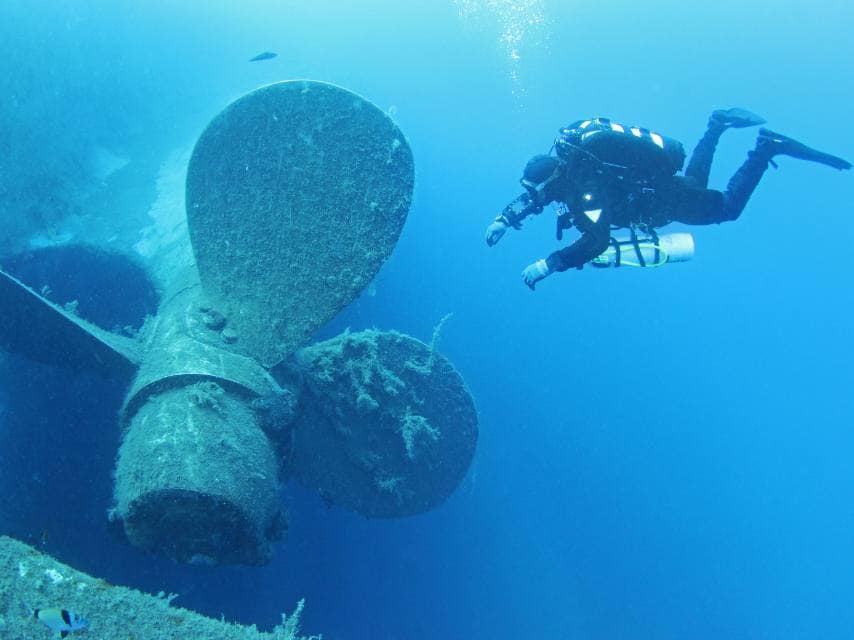 A diver explores the ship's propeller during a guided Zenobia wreck, Cyprus tour by luxury yacht.