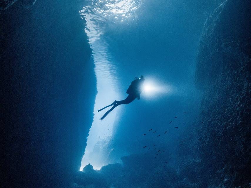Exploring coral-covered walls while diving the Blue Cave of Biševo, one of the best diving spots in Croatia during a luxury yacht charter.