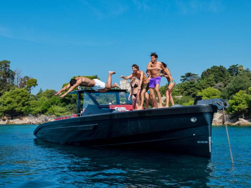 Friends laugh and relax in a tender during a playful moment on their luxury yacht charter in Menorca.