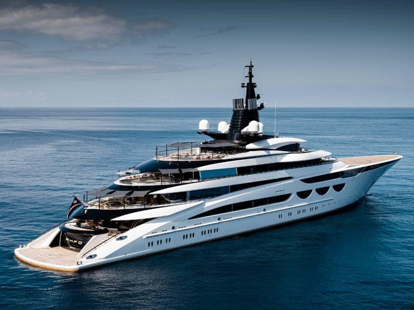 Aerial view of AHPO a luxury yacht displaying yacht registration flags while cruising in open waters.