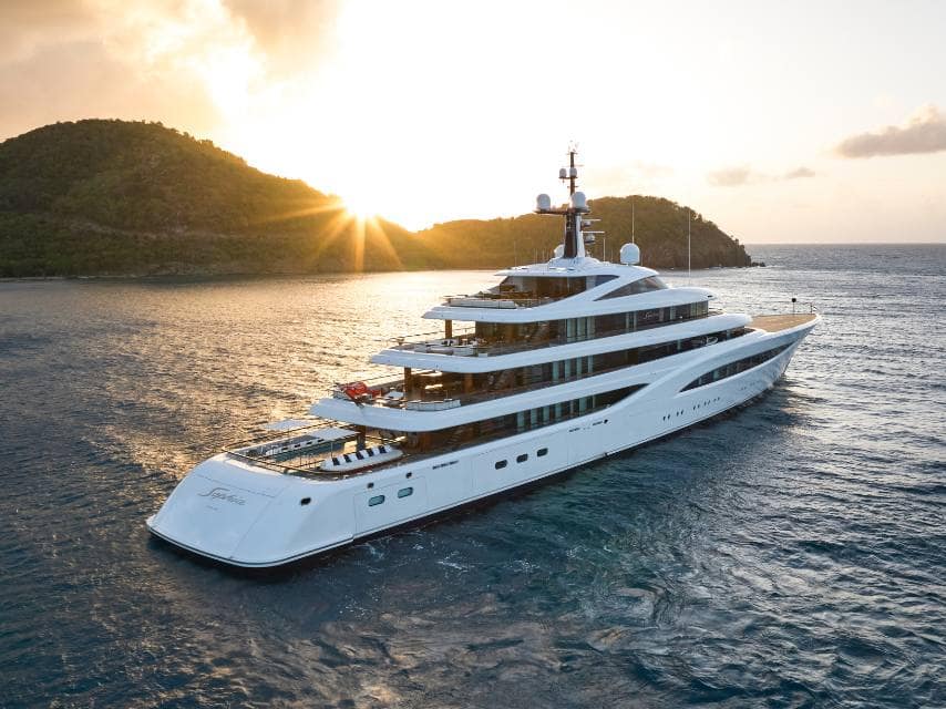 A British flag state yacht is visible as the SOPHIA superyacht sails through open waters at sunset.