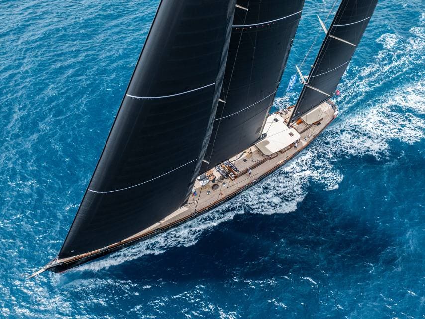 A sailing yacht cruises crystal-clear waters to quiet Mediterranean destinations for the ultimate tranquil experience.